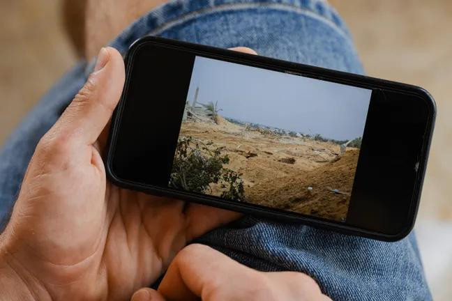 Израильский солдат Юваль Грин показывает на экране телефона фотографию разрушений в Хан-Юнисе: вокруг лишь песок и обломки. Фото: Йонас Опперскальски / DER SPIEGEL