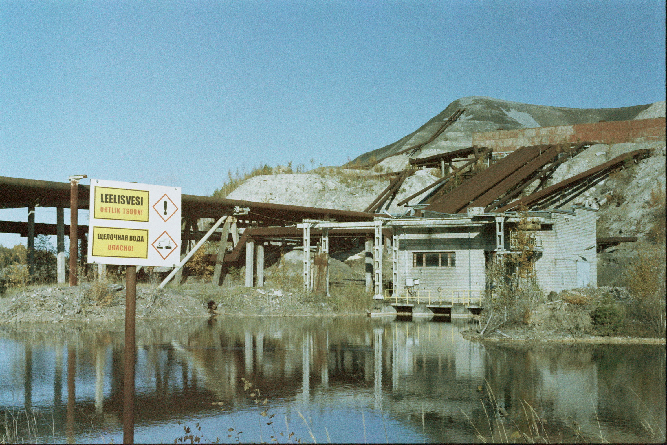 “Alkaline water, danger” Bilingual sign in Estonian and Russian close to a shale oil factory, Ida-Viru County, Estonia 