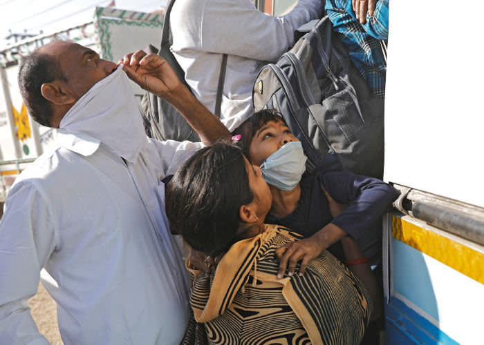 На&nbsp;окраине Дели 29&nbsp;марта: женщина с&nbsp;дочерью пытаются сесть в&nbsp;переполненный автобус, чтобы уехать домой в&nbsp;деревню © Reuters 