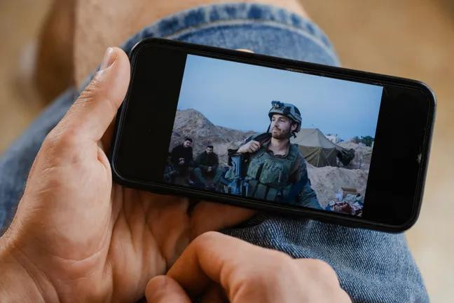 Израильский солдат Юваль Грин показывает на своем телефоне фотографию, сделанную в Хан-Юнисе в конце 2023 года: он единственный из десяти солдат, кто выступает открыто, не скрывая своего имени. Фото: Йонас Опперскальски / DER SPIEGEL
