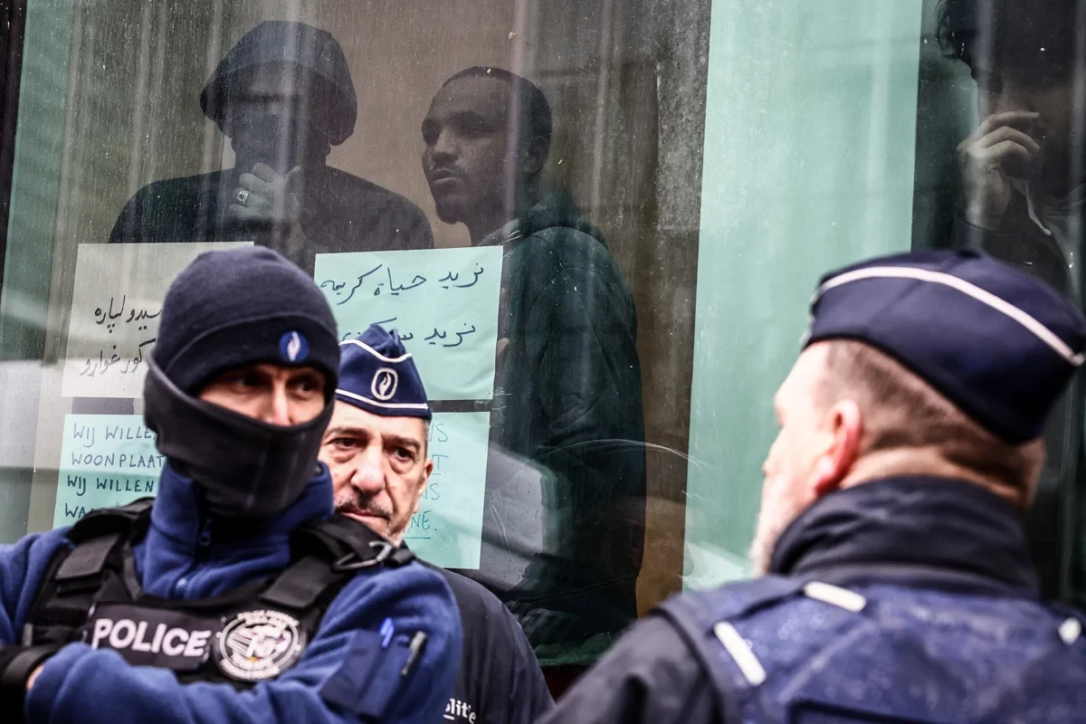 Бельгийские полицейские на фоне мигрантов, Брюссель, 14 марта 2023 года. Фото: Stephanie Lecocq / EPA