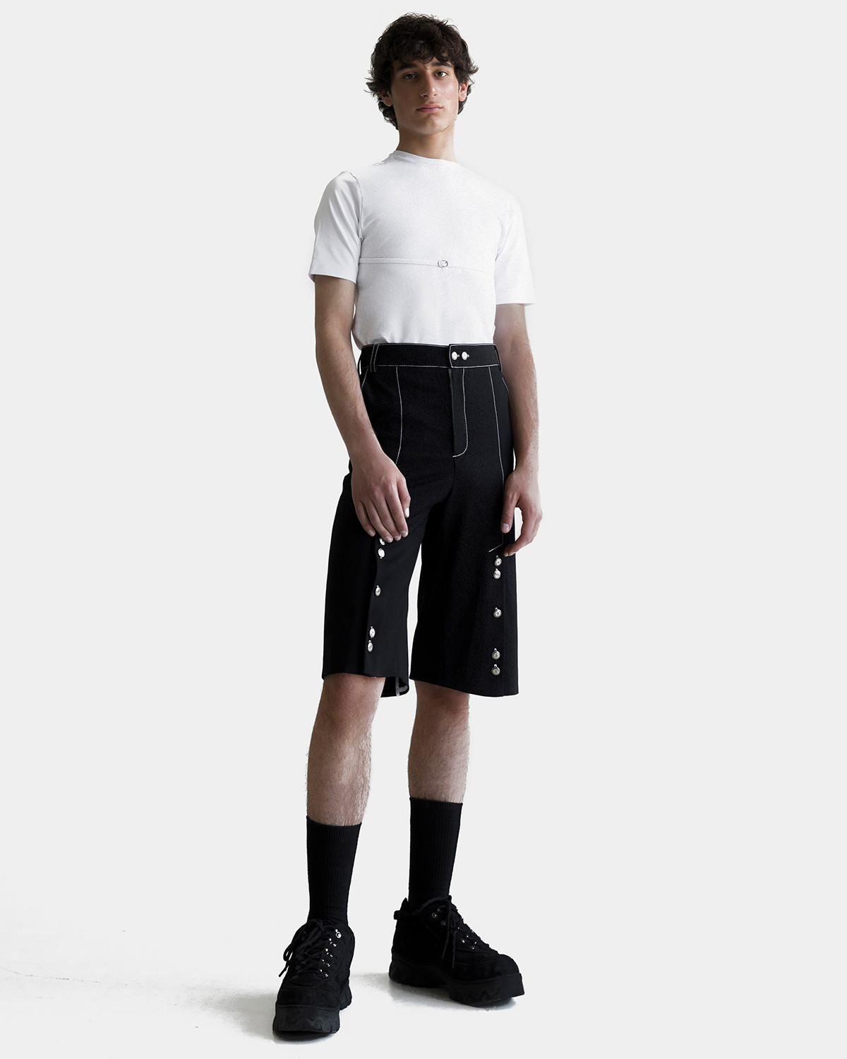 Alex is wearing a white BOYFRIEND belt t-shirt and black buttoned BOYFRIEND shorts by Ruslan Nasir